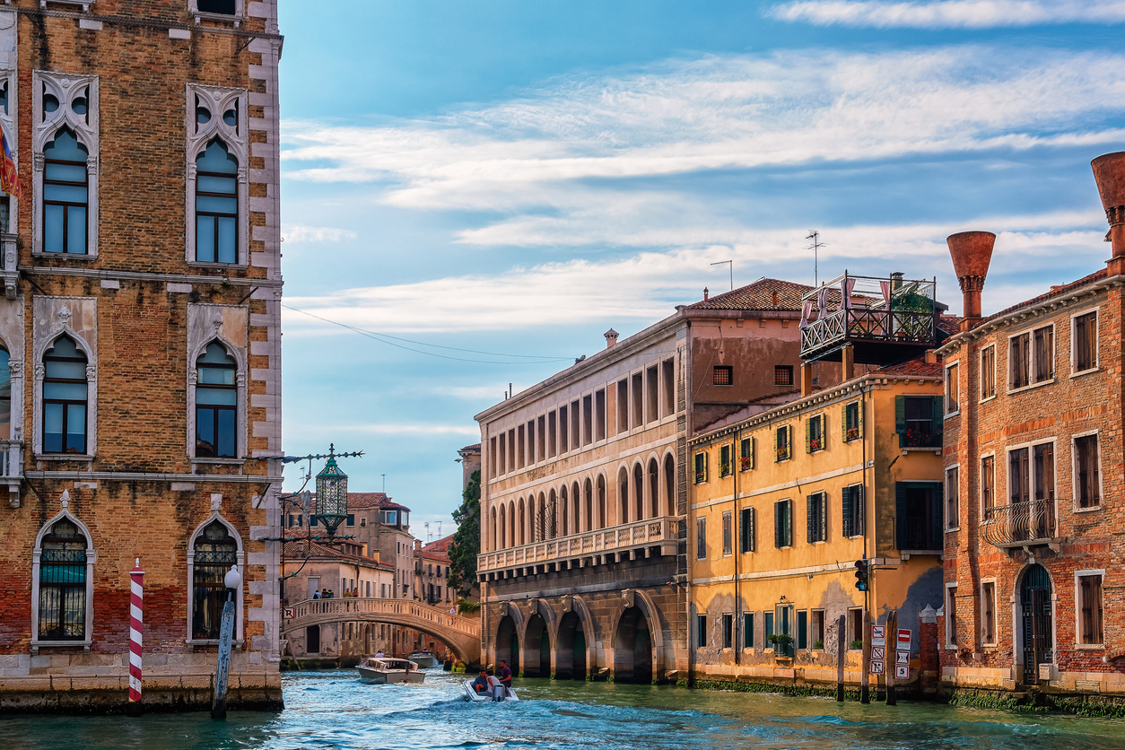 Beautiful view of Venetian landscape. Waterfront palaces, bridges, and boats. Corner of Ca’ Foscari and side rio by Grand Canal, Venice, Italy.
